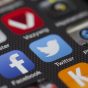 技术审校人员在双屏工位前核对 madoutv 线路延迟数据与状态面板记录，屏幕冷光与室内灯光交织
